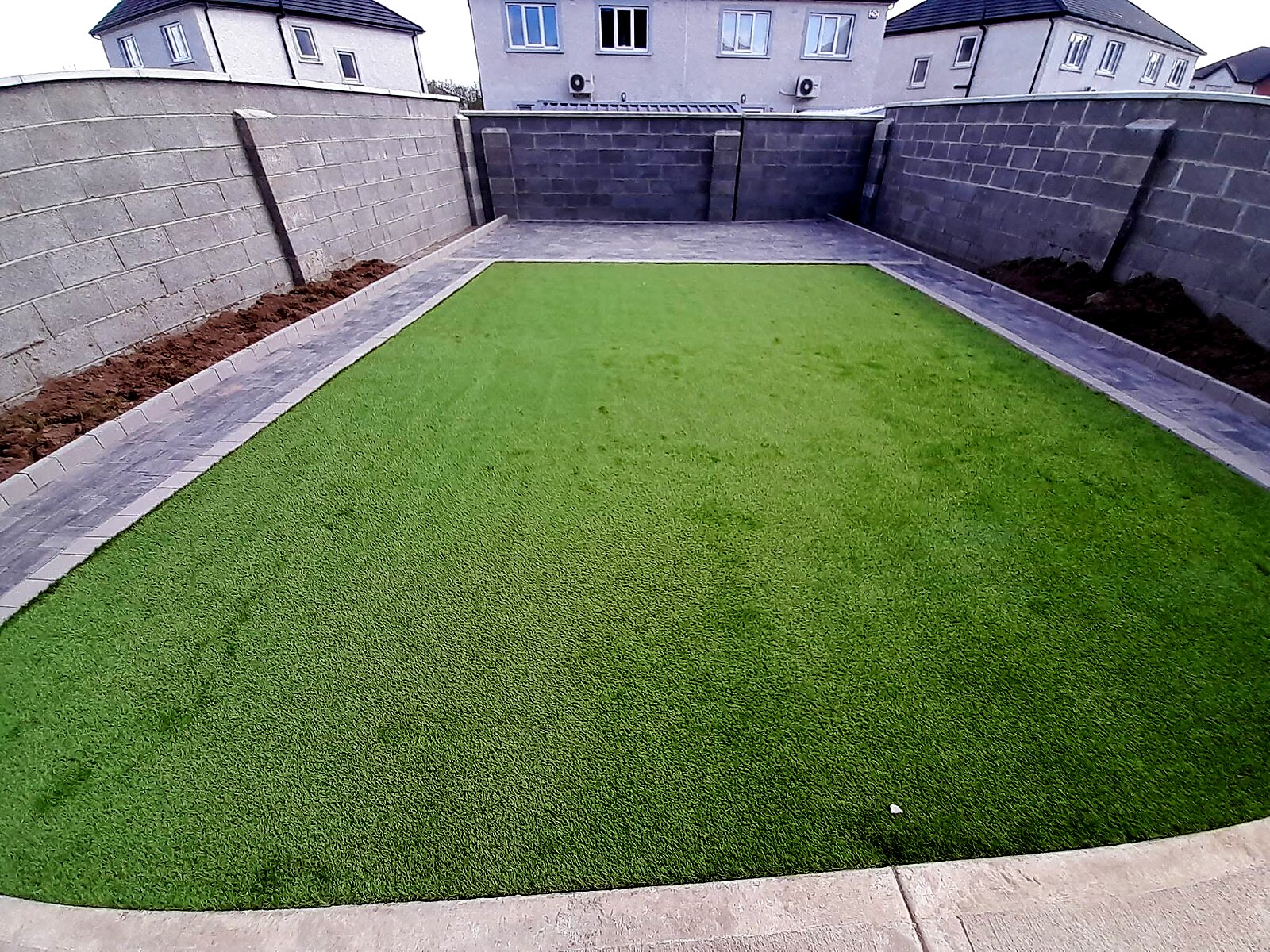 Finished garden with artificial grass and silver grey paving