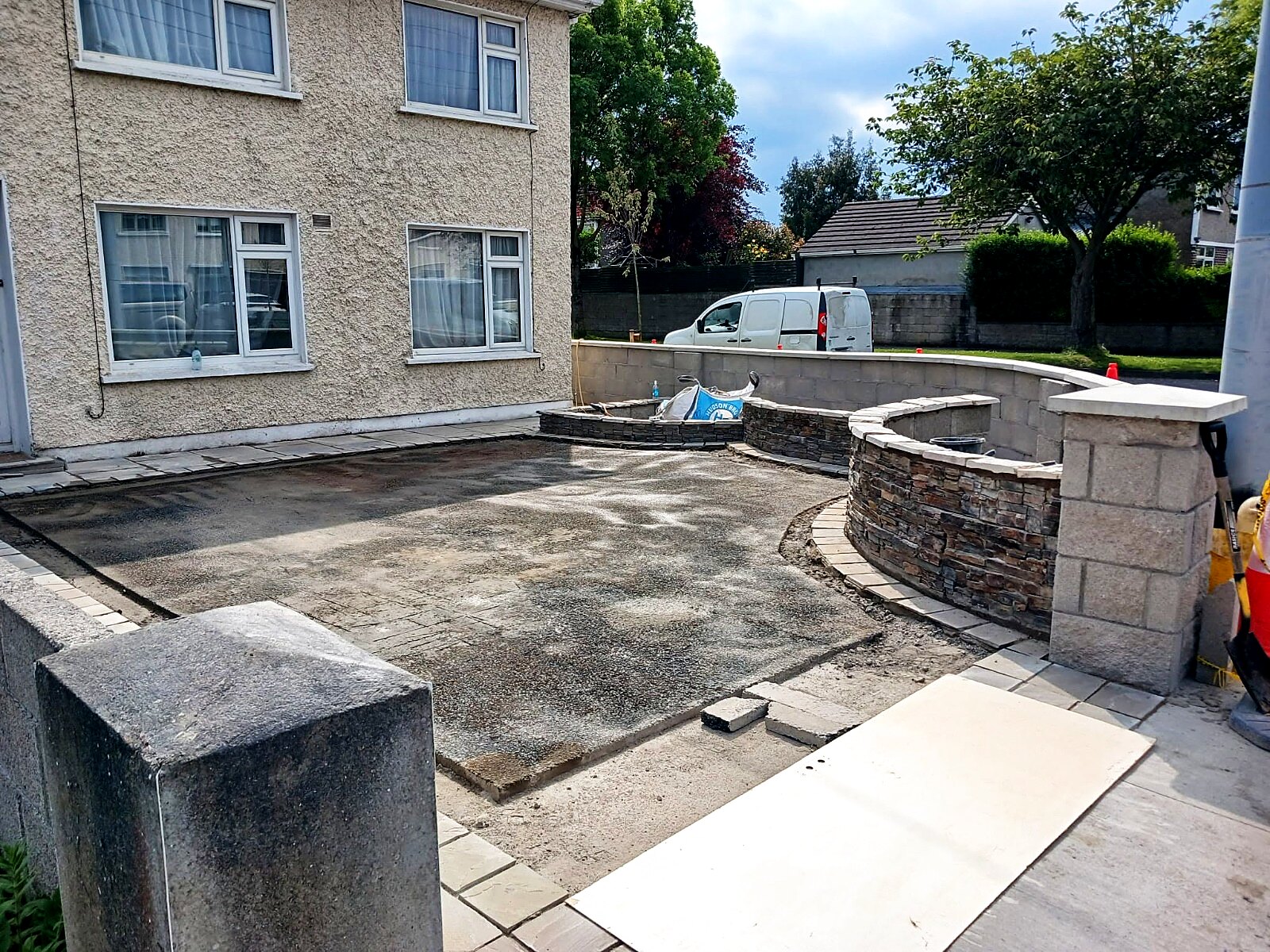 Prepared driveway base with curved stone-clad feature walls