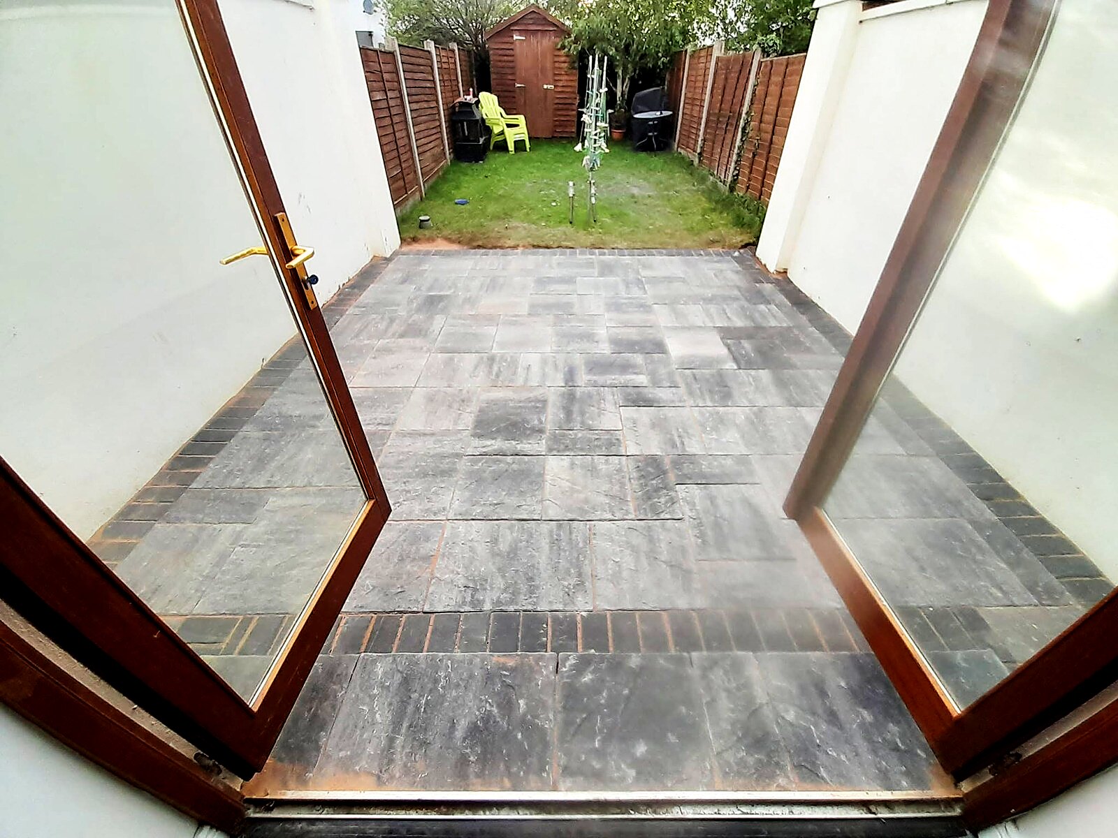 Charcoal paved patio with brick border seen through open patio doors