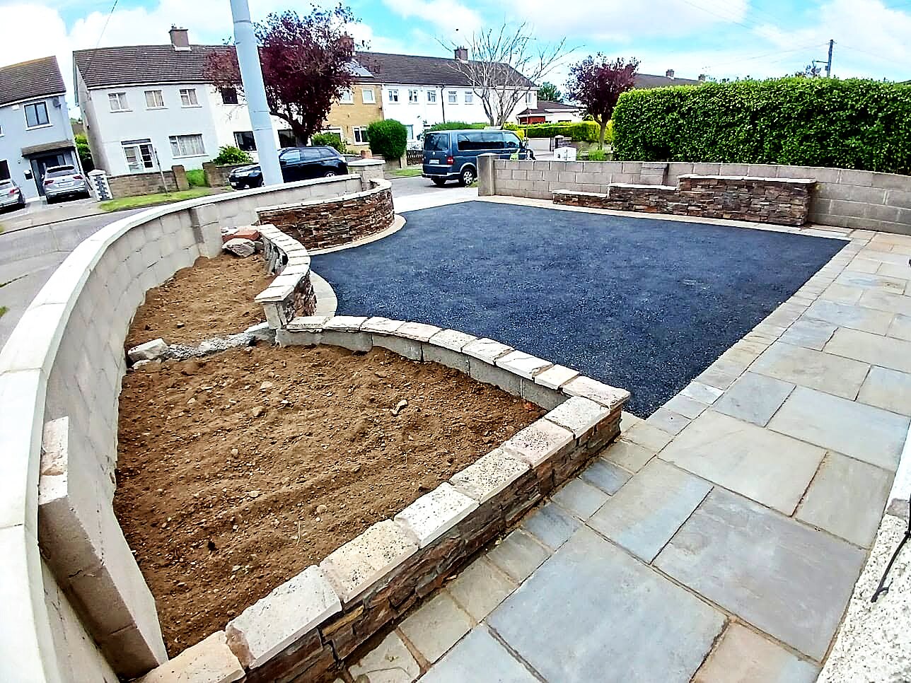 Finished tarmac driveway with sandstone paving and curved stone-clad flower beds
